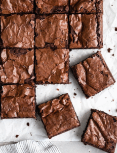  A close-up of a rich brownie square resting on a clean white surface, showcasing its fudgy texture and chocolatey color.