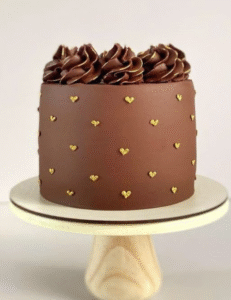  A rich chocolate cake topped with decorative gold hearts, creating an elegant and festive appearance.<br />
