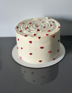  A white cake topped with red hearts, elegantly decorated for a celebration or special occasion.<br />

